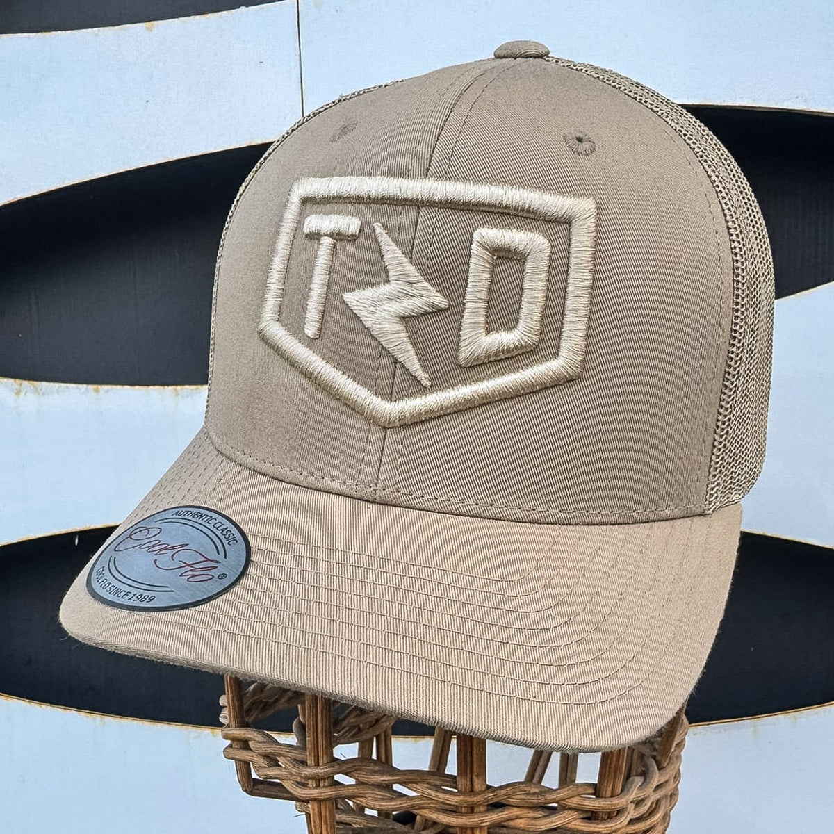 Beige cap with logo on a mannequin head against a blue background